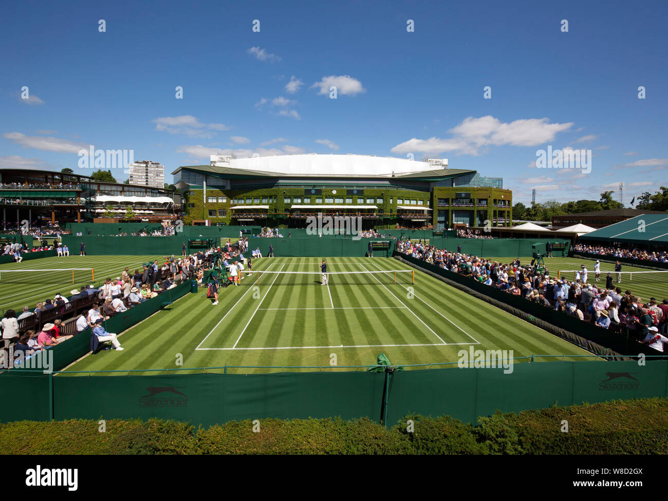 Vista panoramica di tribunali esterno con corte centrale edificio in background, 2019 campionati di Wimbledon, London, England, Regno Unito Foto Stock