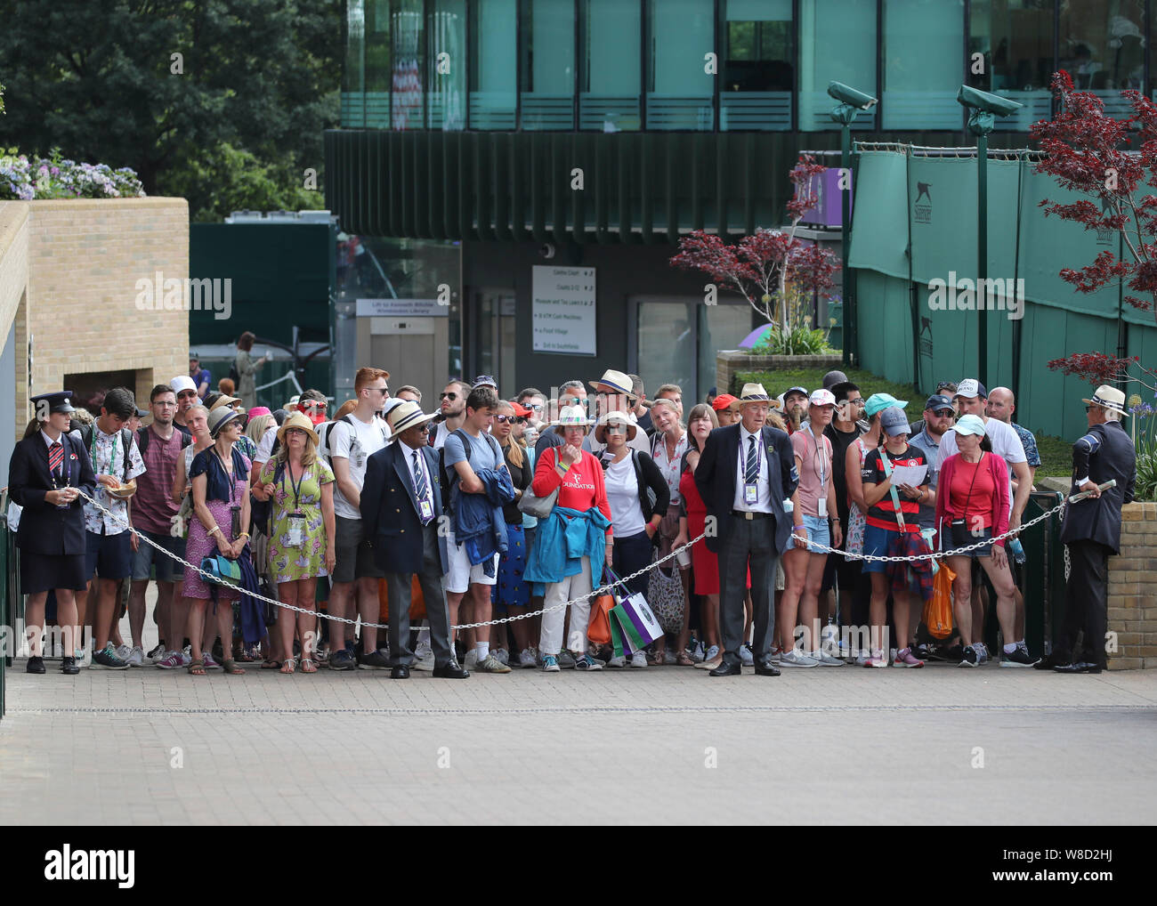 Il personale di sicurezza tenere indietro la folla prima dei cancelli aperti durante il 2019 campionati di Wimbledon, London, England, Regno Unito Foto Stock