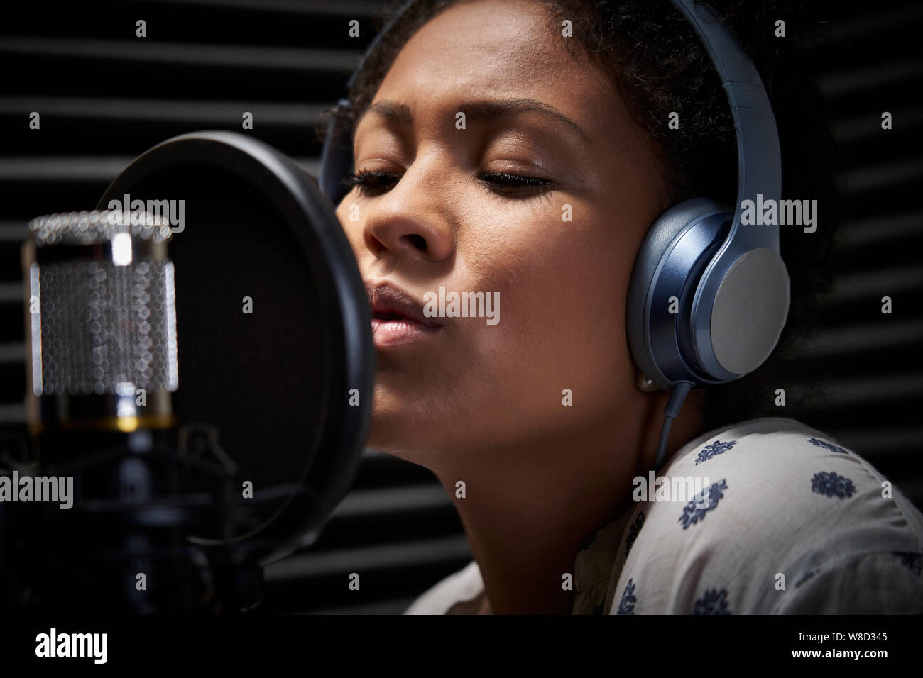 Vocalist femminile che indossano le cuffie a cantare nel microfono in studio di registrazione Foto Stock