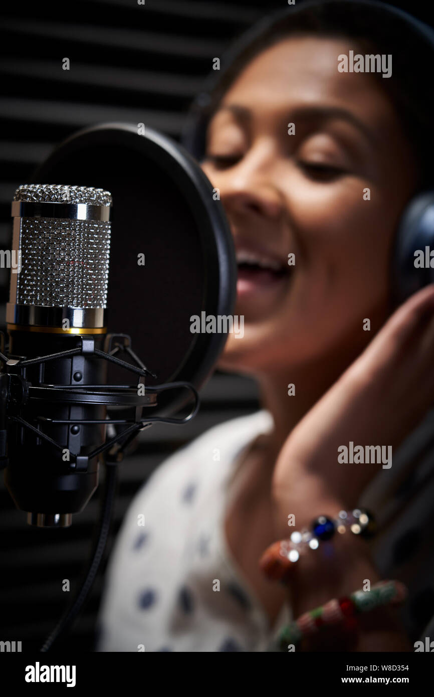Vocalist femminile che indossano le cuffie a cantare nel microfono in studio di registrazione Foto Stock