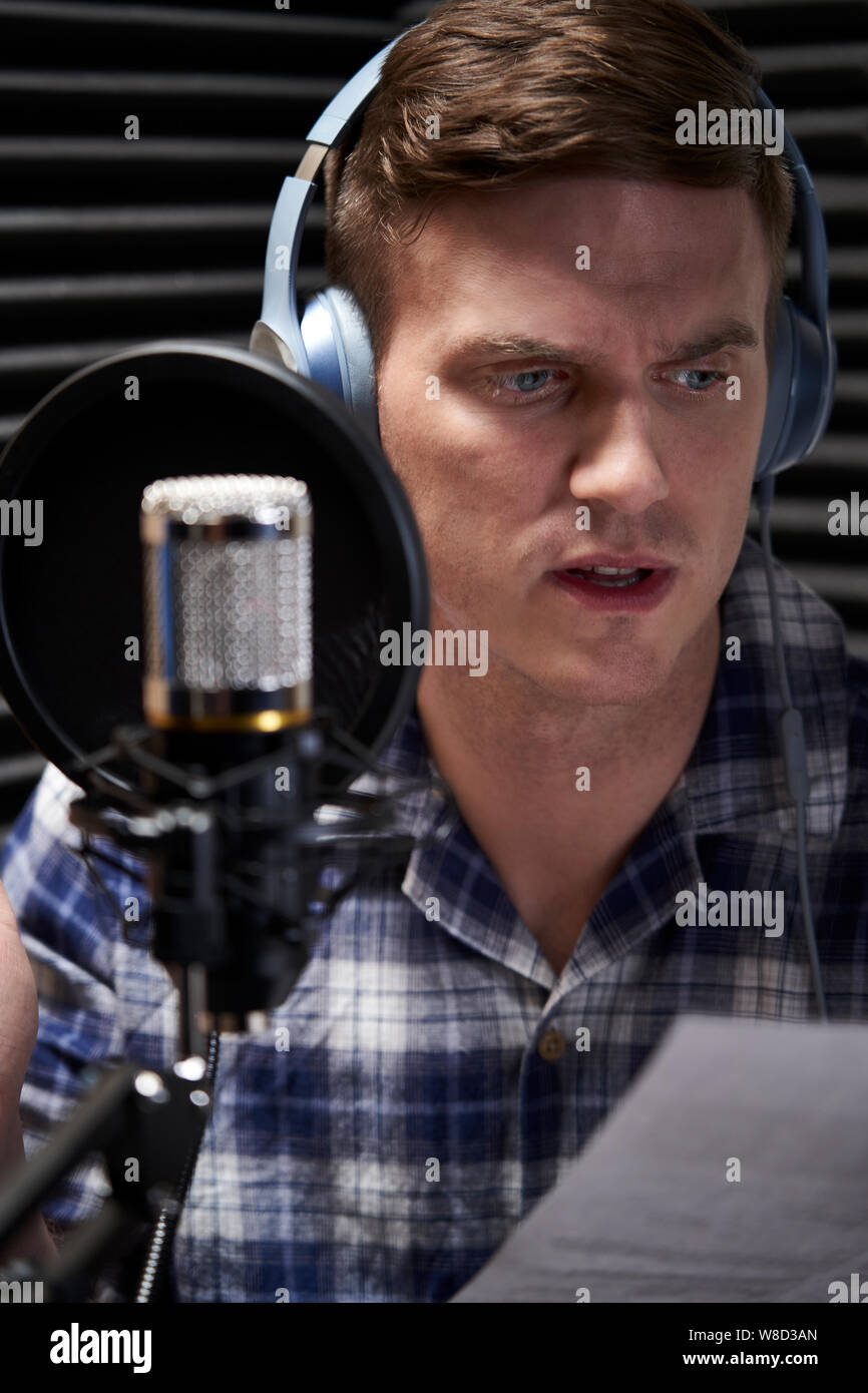 Artista di voiceover in studio di registrazione la lettura da Script nel microfono Foto Stock