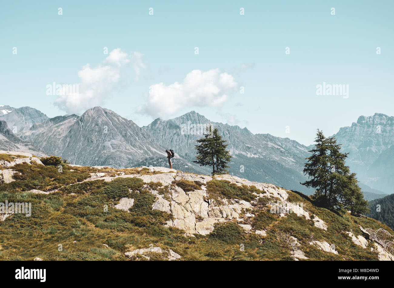 Uomo avventurose escursioni in montagna. In piedi sul bordo di una roccia. Viaggiatori con lo zaino in spalla. Adventure Concept. Uno stile di vita attivo. Hipster vintage st Foto Stock