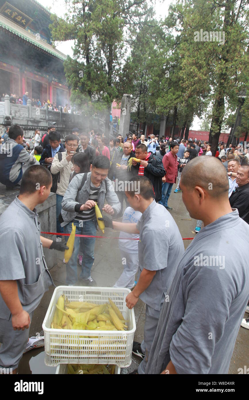 I monaci distribuiscono raccolte mais per i turisti nel tempio di Shaolin sul Monte Songshan (Monte Songshan o una canzone di montagna) nella città di Dengfeng, centrale Foto Stock