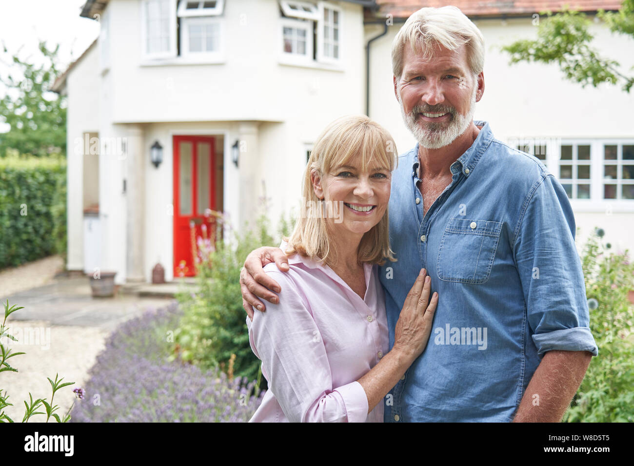 Ritratto di Coppia Matura in piedi nel giardino davanti a casa da sogno in campagna Foto Stock