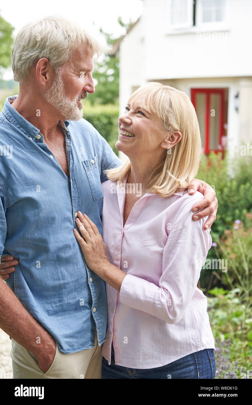Coppia Matura in piedi nel giardino davanti a casa da sogno in campagna Foto Stock