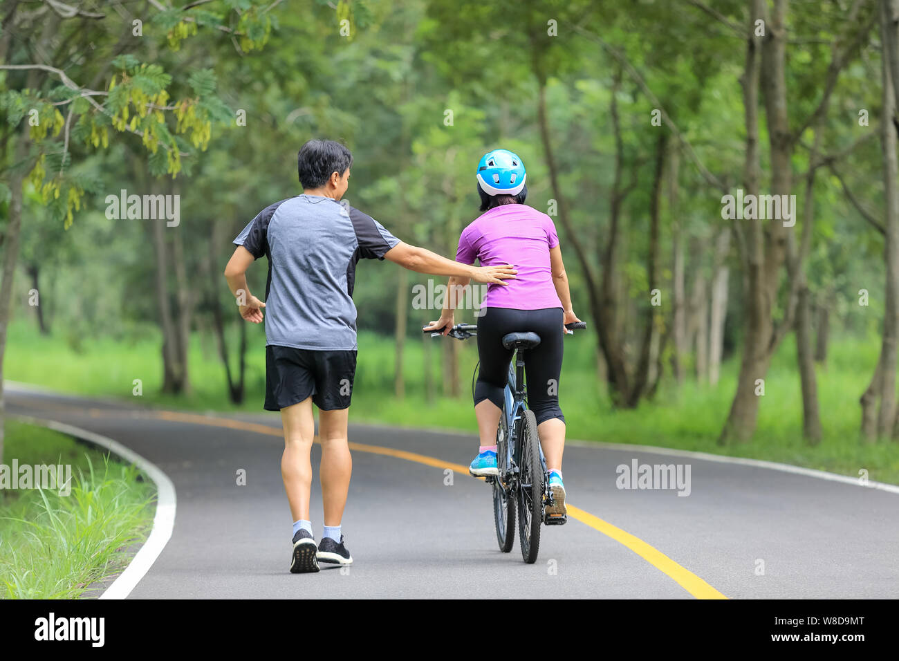 Coppia di mezza età a piedi con la bicicletta in posizione di parcheggio Foto Stock