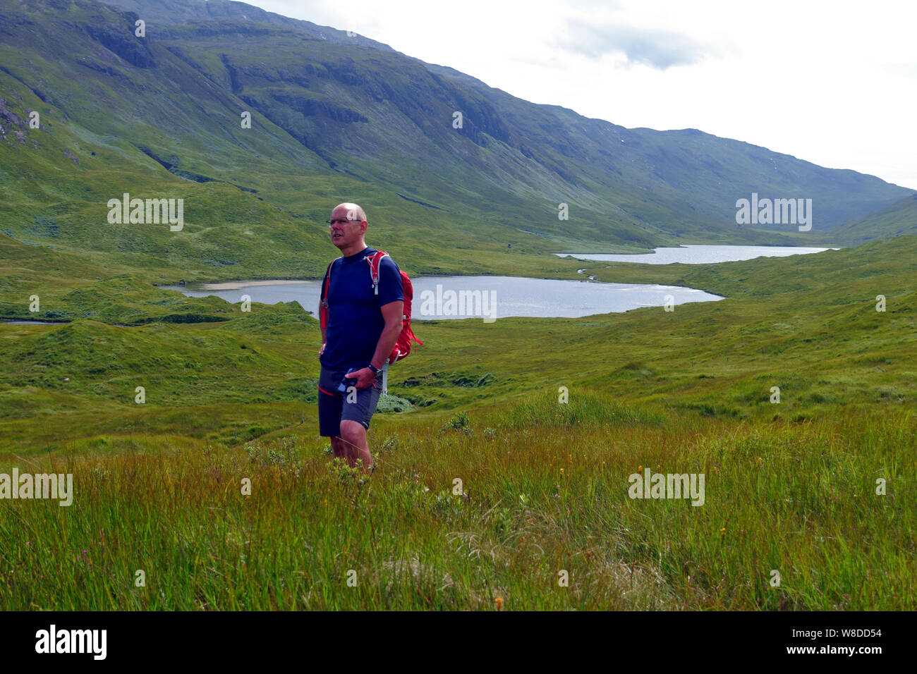 Uomo in piedi in Glen More on the Isle of Mull presso i tre laghi (solo due sono visibili, Loch un Ellen e ulteriore dietro Loch Airde Glais Foto Stock