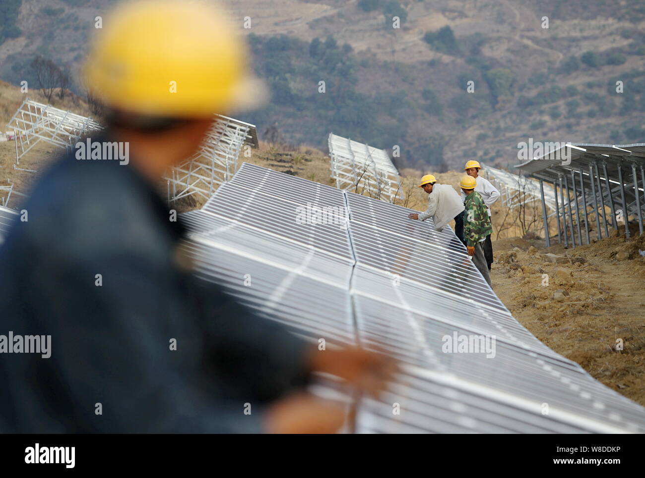 Lavoratori cinesi installare pannelli solari al Wanjiashan Centrale fotovoltaica su Wanjiashan Montagna in Yanbian county, Panzhihua city, a sud-ovest Foto Stock