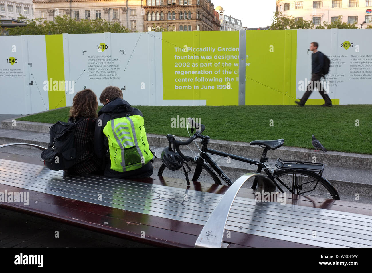 Coppia giovane parlando su un bancone di accaparramento durante un rinnovamento/modernizzazione di Piccadilly Gardens Manchester, Inghilterra UK. fotografia DON TONGE Foto Stock