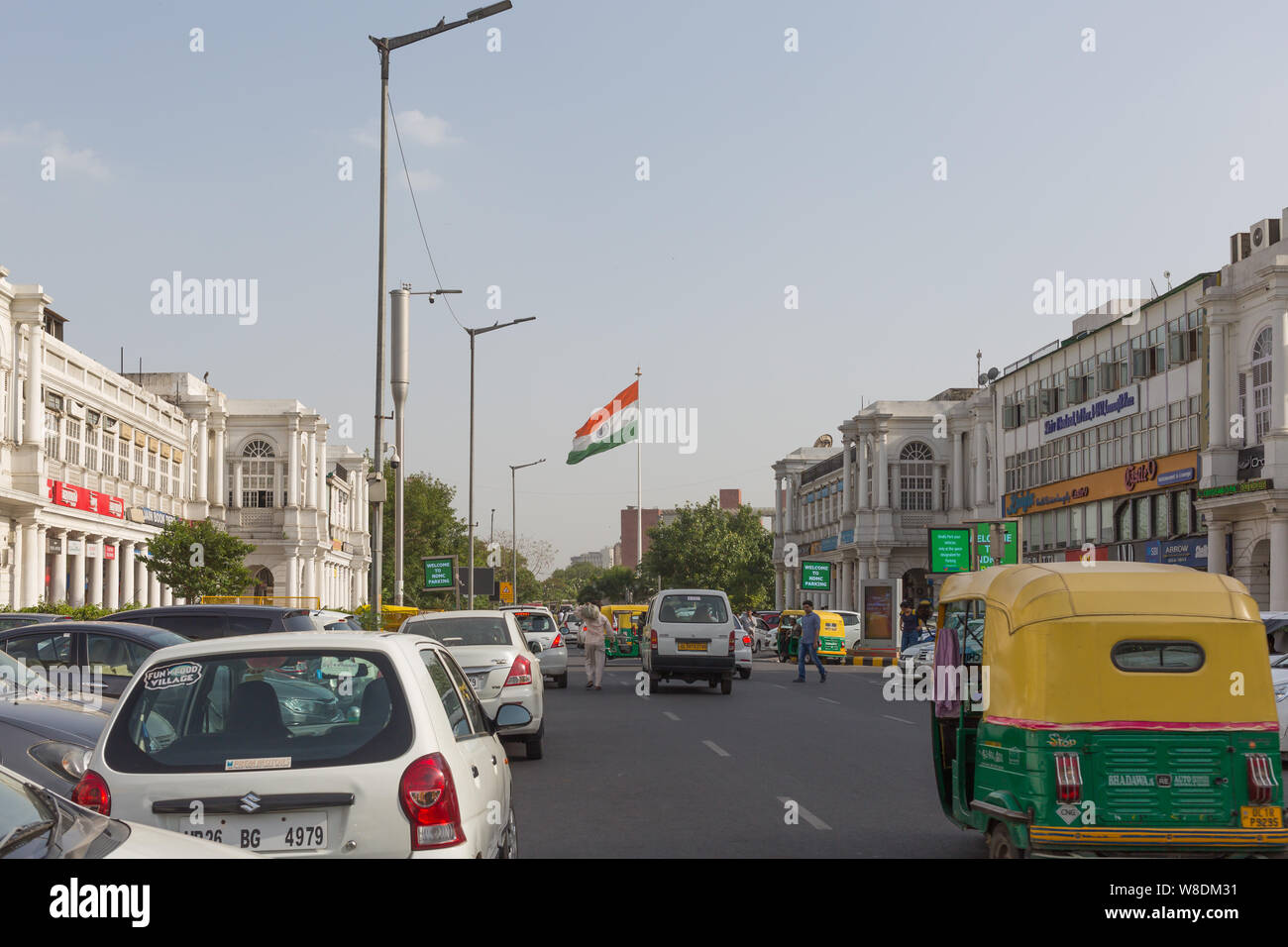 Per i veicoli che circolano su strada con bandiera indiana in background a Connaught Place in New Delhi Foto Stock