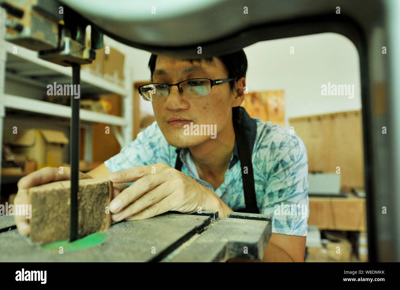 Lavoratore cinese Shao Zhixiu Tagli un pezzo di radica di legno per fare un handmade tubazione del tabacco nel suo laboratorio di Dexing city, est della Cina di provincia dello Zhejiang, Foto Stock