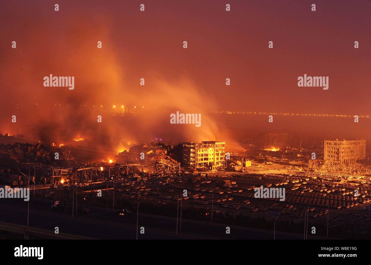 Fumo denso sorge come le automobili importate sono bruciate, edifici e i contenitori sono devastati dalle esplosioni mortale in Binhai Nuova Area di Tianjin, mento Foto Stock