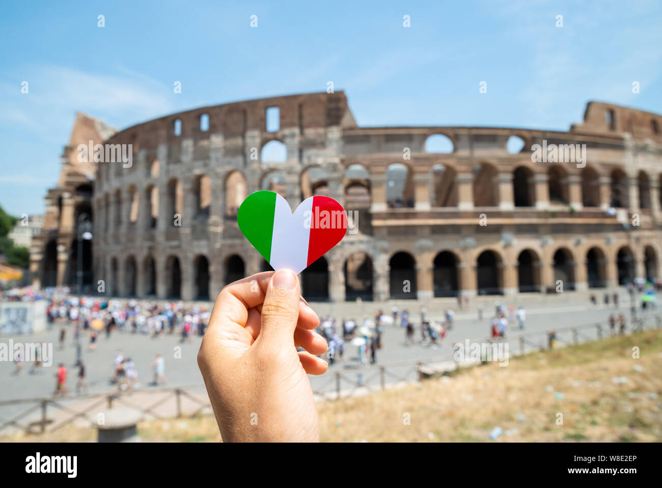 Donna che mantiene a forma di cuore Bandiera Italiana davanti al Colosseo, Italia Foto Stock
