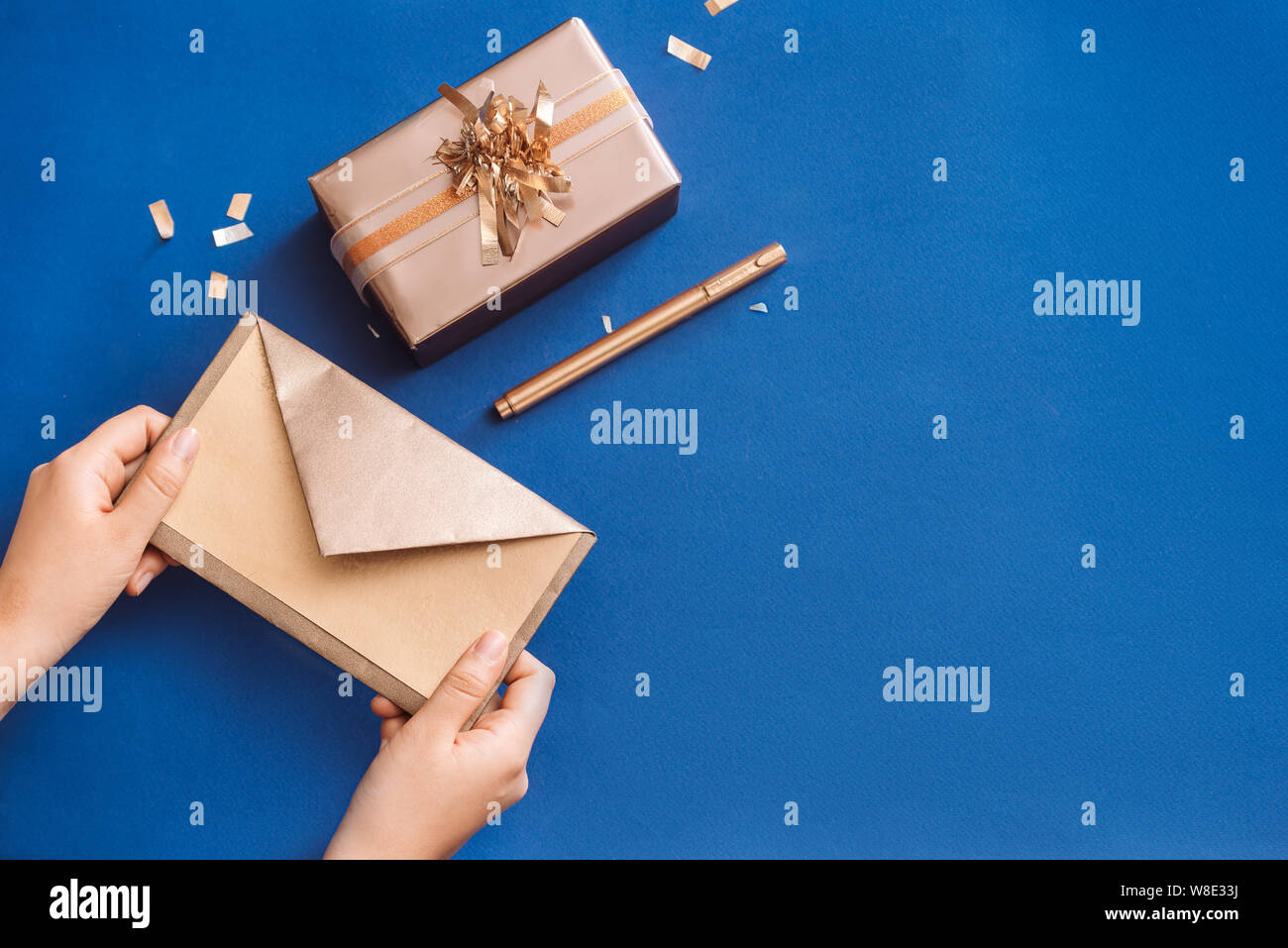 La scrittura di auguri di Natale con gold box e la corona di fiori su sfondo blu Foto Stock
