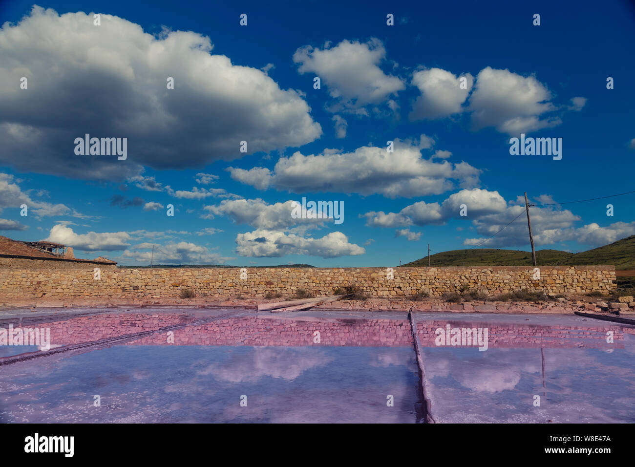 Rosa bacino di sale nella parte anteriore e il verde delle montagne sullo sfondo di un cielo blu chiaro. Foto Stock