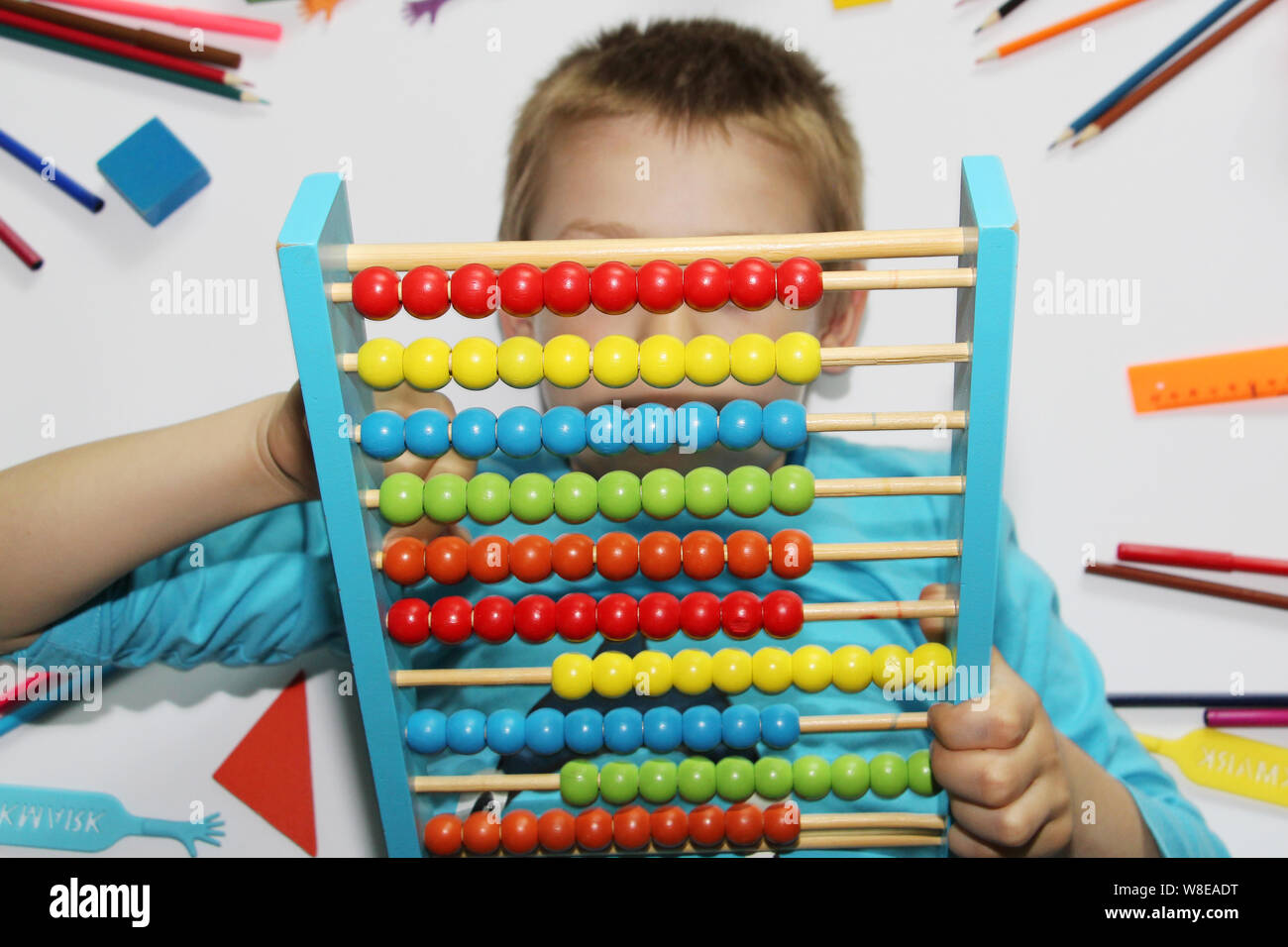 Il ragazzo detiene grandi abacus nelle sue mani. L'Abacus è colorato, multicolore nelle mani di un bambino. Il ragazzo è sempre pronto ad andare a scuola. Il chi Foto Stock