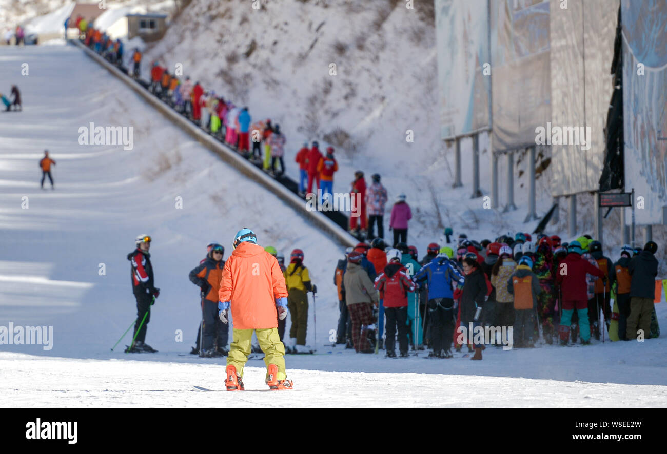 Linea di persone fino a prendere una scala mobile per andare in salita per praticare lo sci in una stazione sciistica in Chongli county, Zhangjiakou, città del nord della Cina nella provincia di Hebei, 5 Foto Stock