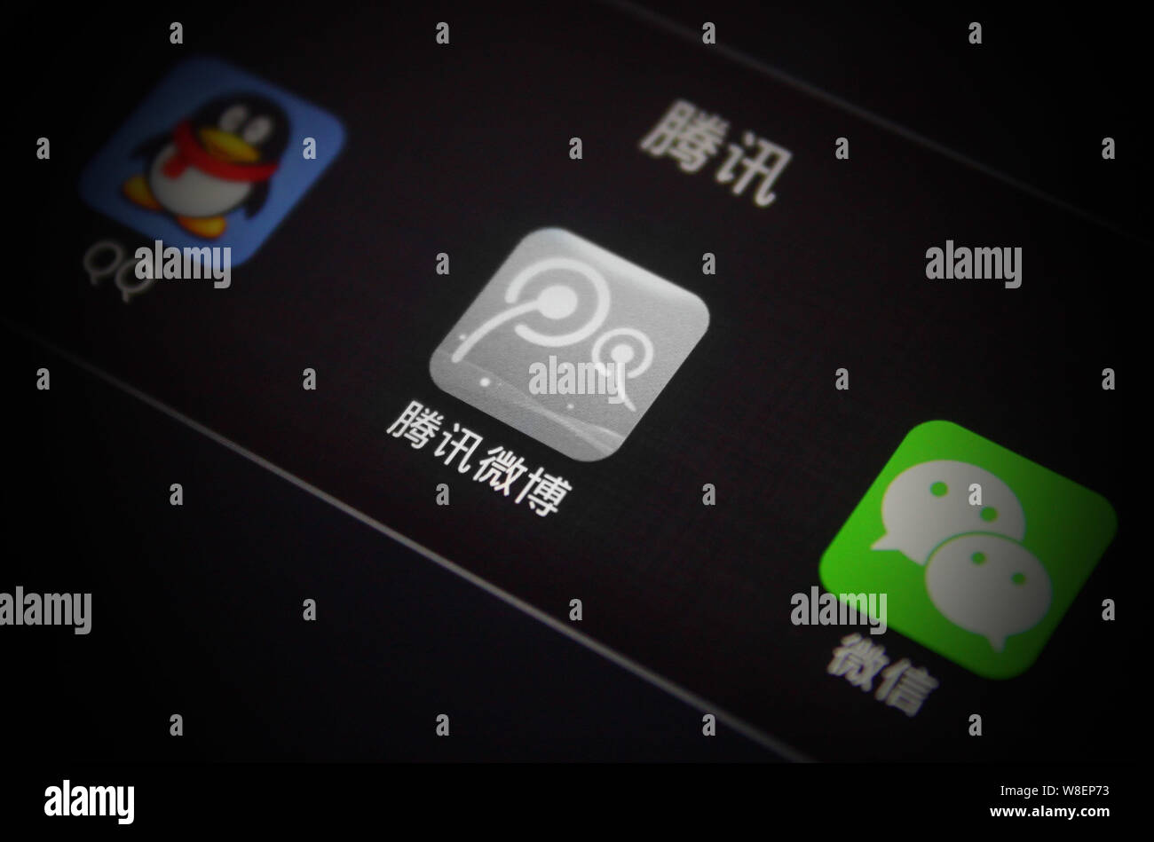 --FILE--un cinese telefono cellulare utente guarda le icone di (da sinistra) messaggistica mobile app QQ, Tencent servizio di microblogging e di messaggistica Weixin app Foto Stock