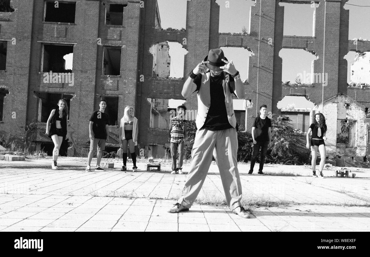 Energico giovane hip hop street dancer eseguendo la sua routine in una piazza urbana guardato dalla sua pista. Foto Stock