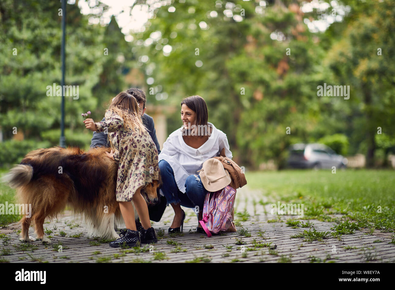 Bella famiglia felice si diverte con un ruvido Collie all'esterno. Madre, padre e figlia sono in esecuzione con il cane nel parco. Foto Stock
