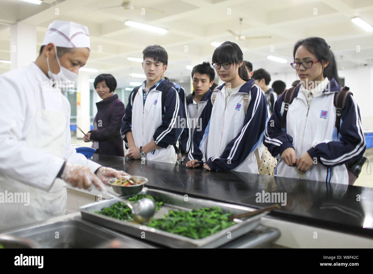 --FILE -- Gli studenti in coda fino a ottenere la loro cena in una mensa per una high school di Hangzhou, a est della Cina di provincia dello Zhejiang, 1 aprile 2014. Persone che ho Foto Stock