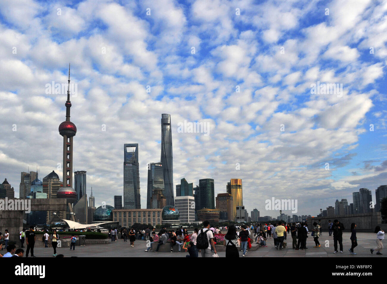 I turisti a piedi lungo la passeggiata sul Bund contro lo skyline di grandi edifici e grattacieli del quartiere finanziario di Lujiazui durante il Foto Stock