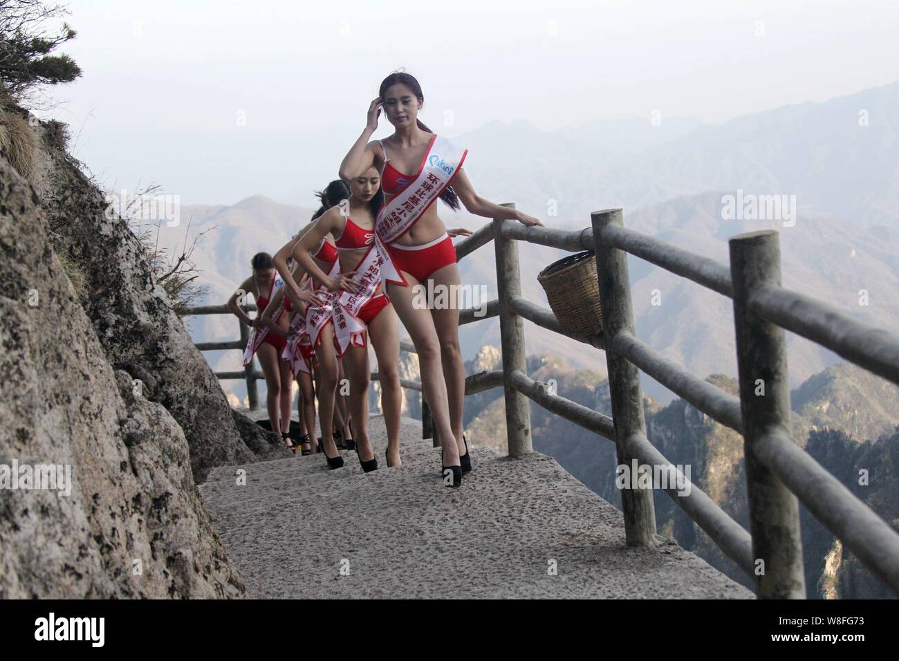 Bikini-modelli di vestiti a piedi in tacchi alti su una passerella sul precipizio di una montagna durante un concorso di bellezza nella contea di Luanchuan, centrale della Cina di Henan Foto Stock