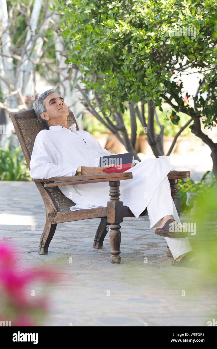 Uomo anziano che si rilassa in giardino Foto Stock