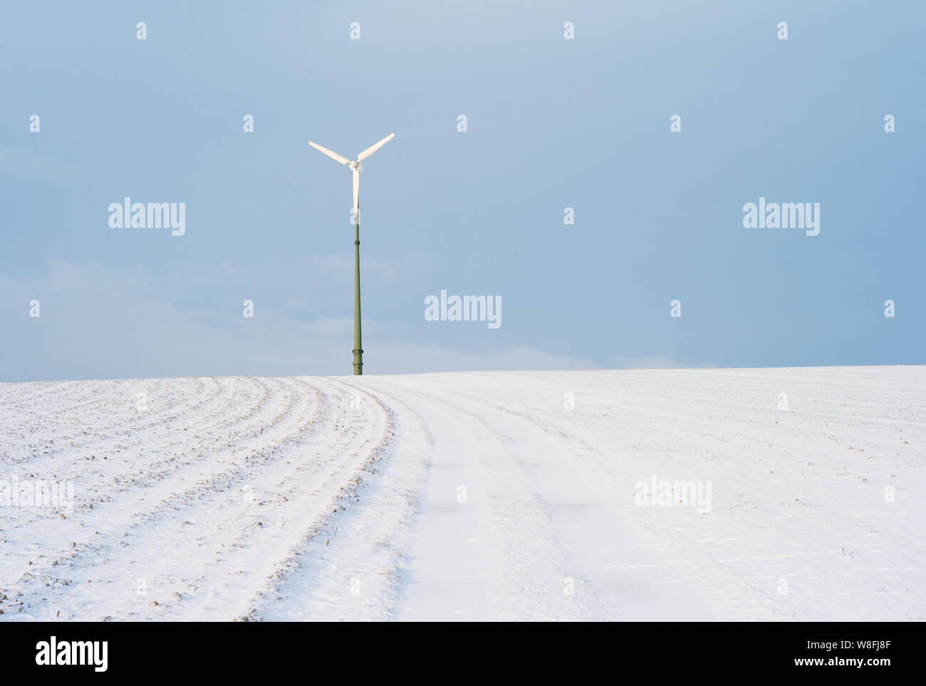 Vento elettrico impianto di alimentazione su una coperta di neve Hill - un concetto per le Energie Rinnovabili Foto Stock