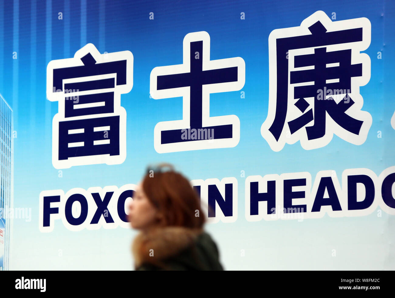 --FILE--A passeggiate a piedi passato un cartello del quartier generale Foxconn edificio in costruzione a Pudong, Shanghai, Cina, 6 febbraio 2015. Aff Foto Stock