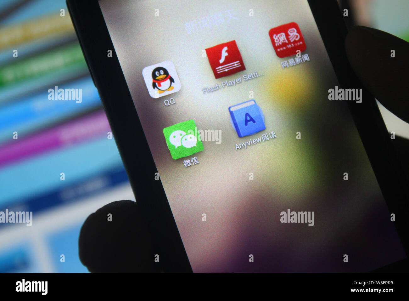 --FILE--un cinese telefono cellulare utente guarda le icone della messaggistica mobile apps QQ, in alto a sinistra e Weixin (WeChat), inferiore sinistro di Tencent sul suo sma Foto Stock