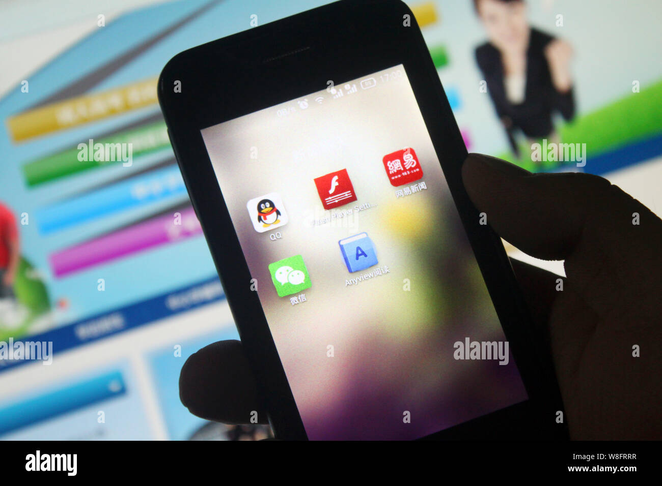 --FILE--un cinese telefono cellulare utente guarda le icone della messaggistica mobile apps QQ, in alto a sinistra e Weixin (WeChat), inferiore sinistro di Tencent sul suo sma Foto Stock