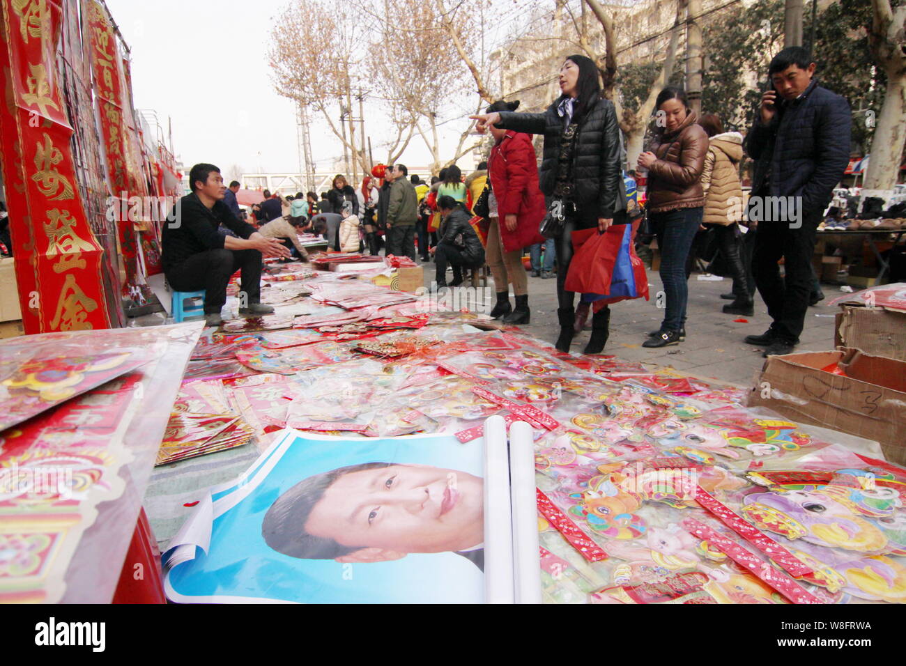 Locali residenti cinesi comprare le decalcomanie rosse e le immagini del Presidente cinese Xi Jinping per la festa di primavera per festeggiare il nuovo anno lunare cinese a roa Foto Stock