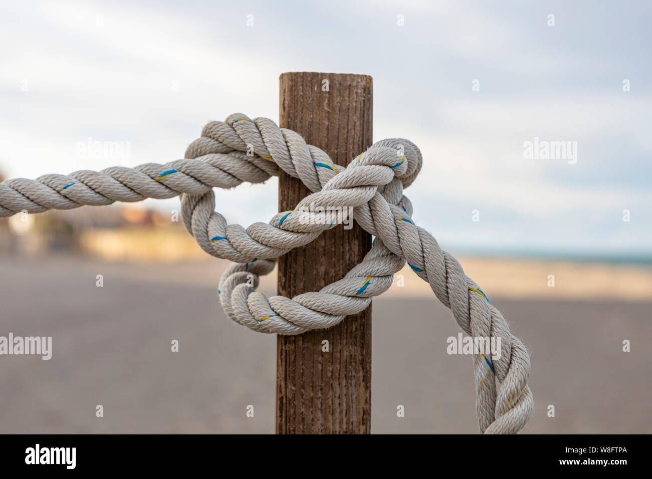Una corda legata intorno ad un palo su una spiaggia. Foto Stock