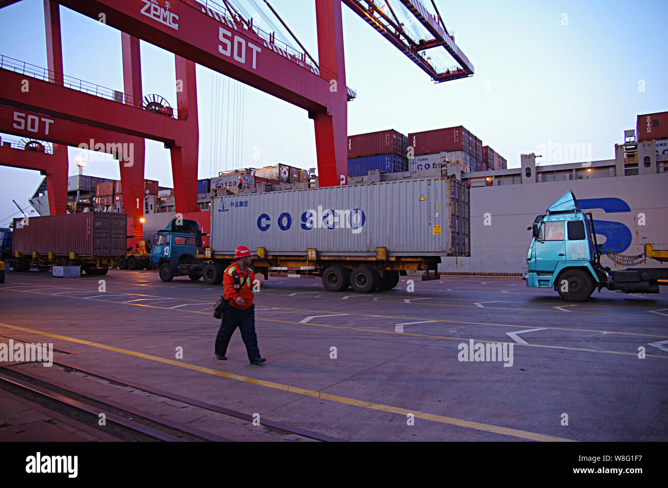 --FILE--un lavoratore cinese passeggiate passato un autocarro caricato con un contenitore di COSCO su una banchina del porto di Rizhao nella città di Rizhao, est della Cina di Shandong pro Foto Stock
