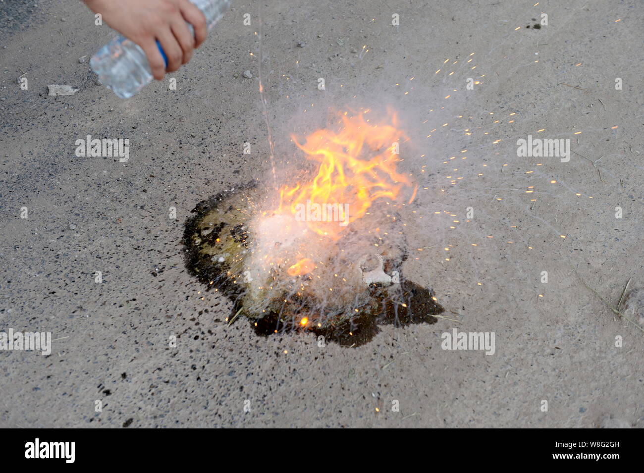 Esso brucia ferocemente dopo un giornalista si versa acqua in bottiglia su un pool di combustibile sulla chimica del suolo vicino al sito del massiccio di blasti di Binh Foto Stock