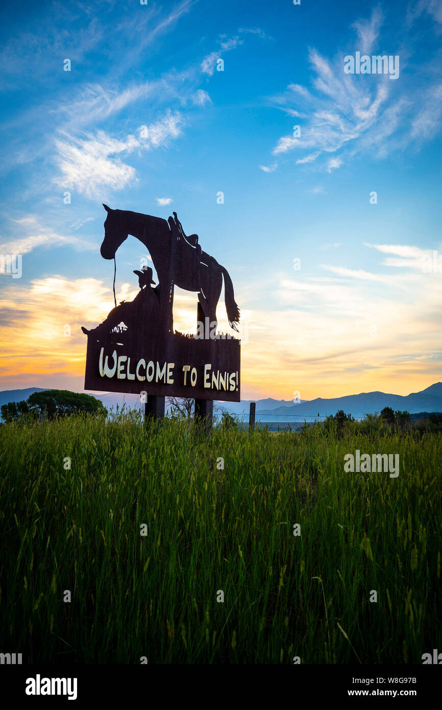 Il pittoresco Cartello in metallo dotato di un cowboy in appoggio sotto il suo cavallo a Ennis, Montana presso sunrise 7/10/2018 Foto Stock