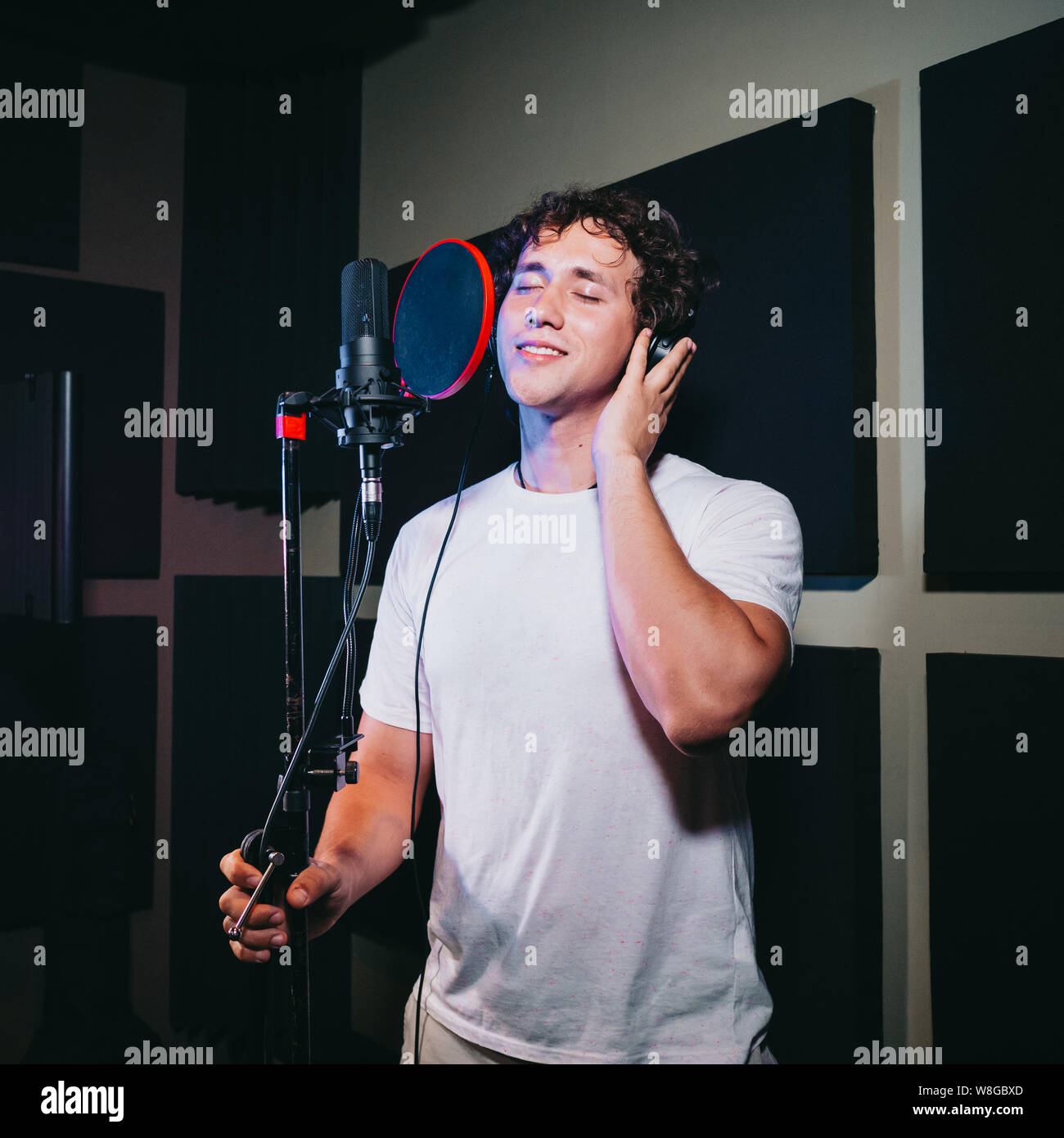 Un espressivo uomo che canta una canzone in un microfono in uno studio di registrazione. Foto Stock