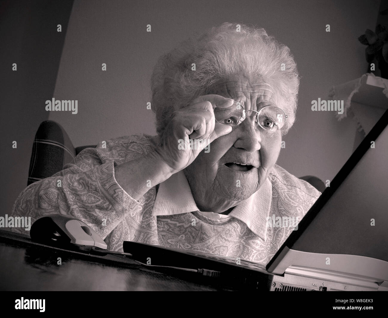 Senior anziani old Lady di casa utilizzando il computer laptop tecnologia è stupito e affascinato dalla sua lo schermo del computer portatile retrò B&W tonica RGB Foto Stock