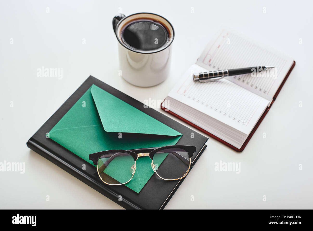 Isolato tazza di caffè, Busta, penna, i notebook e i bicchieri giacenti su uno sfondo bianco. Inquadratura orizzontale Foto Stock