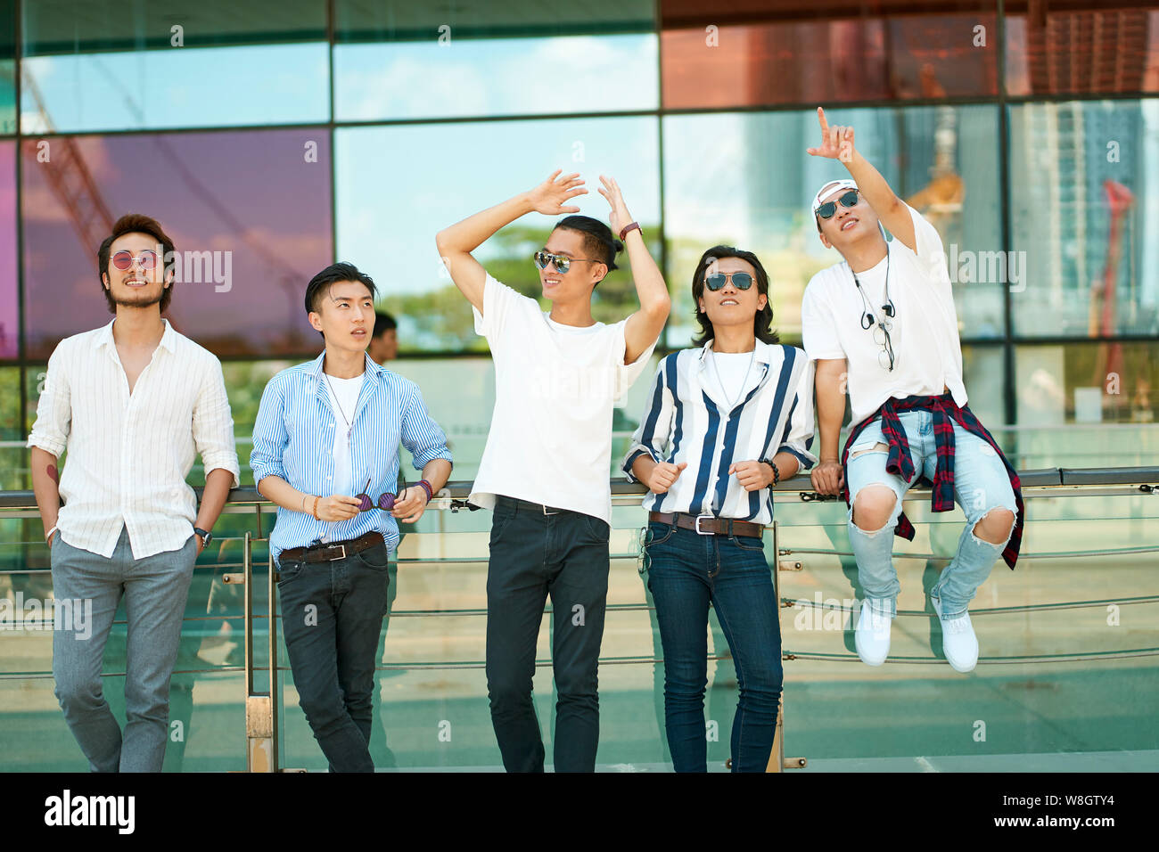 Un gruppo di cinque giovani adulti asiatici appendere fuori insieme sulla strada Foto Stock