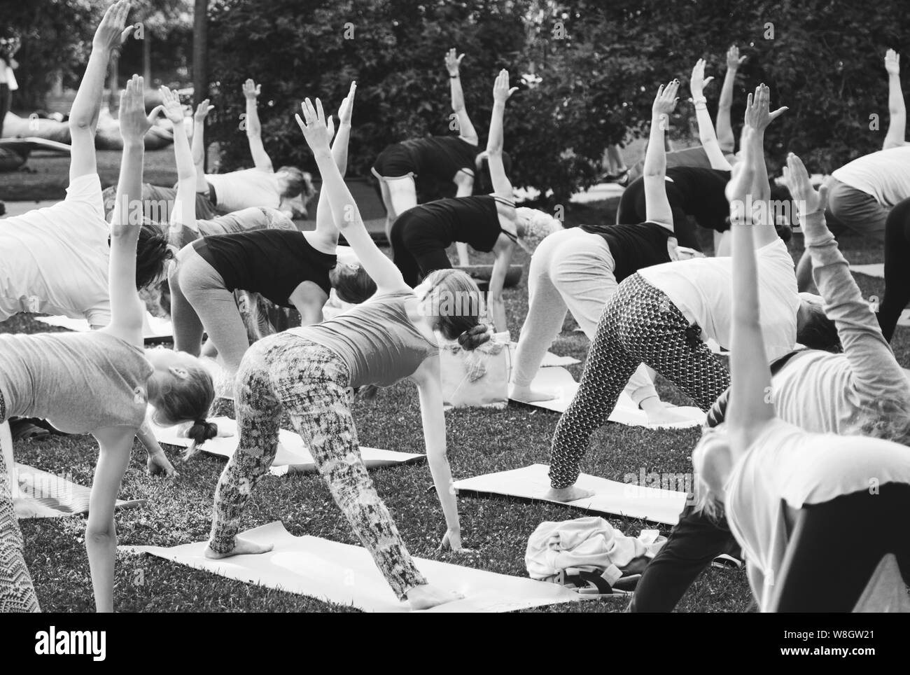 Un gruppo di giovani fare yoga nel parco al tramonto Foto Stock