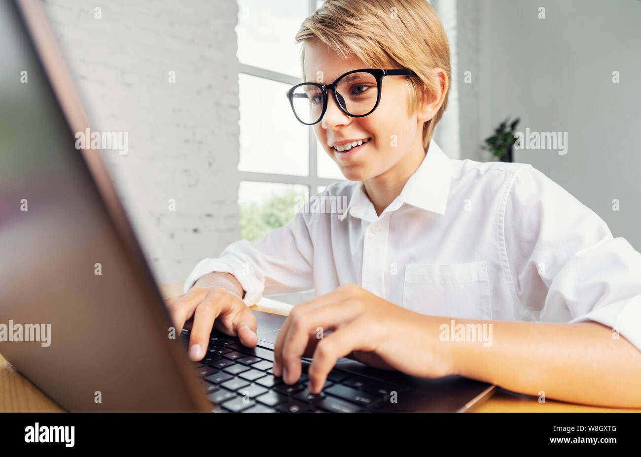 Ragazzo sorridente in bicchieri utilizzando laptop Foto Stock