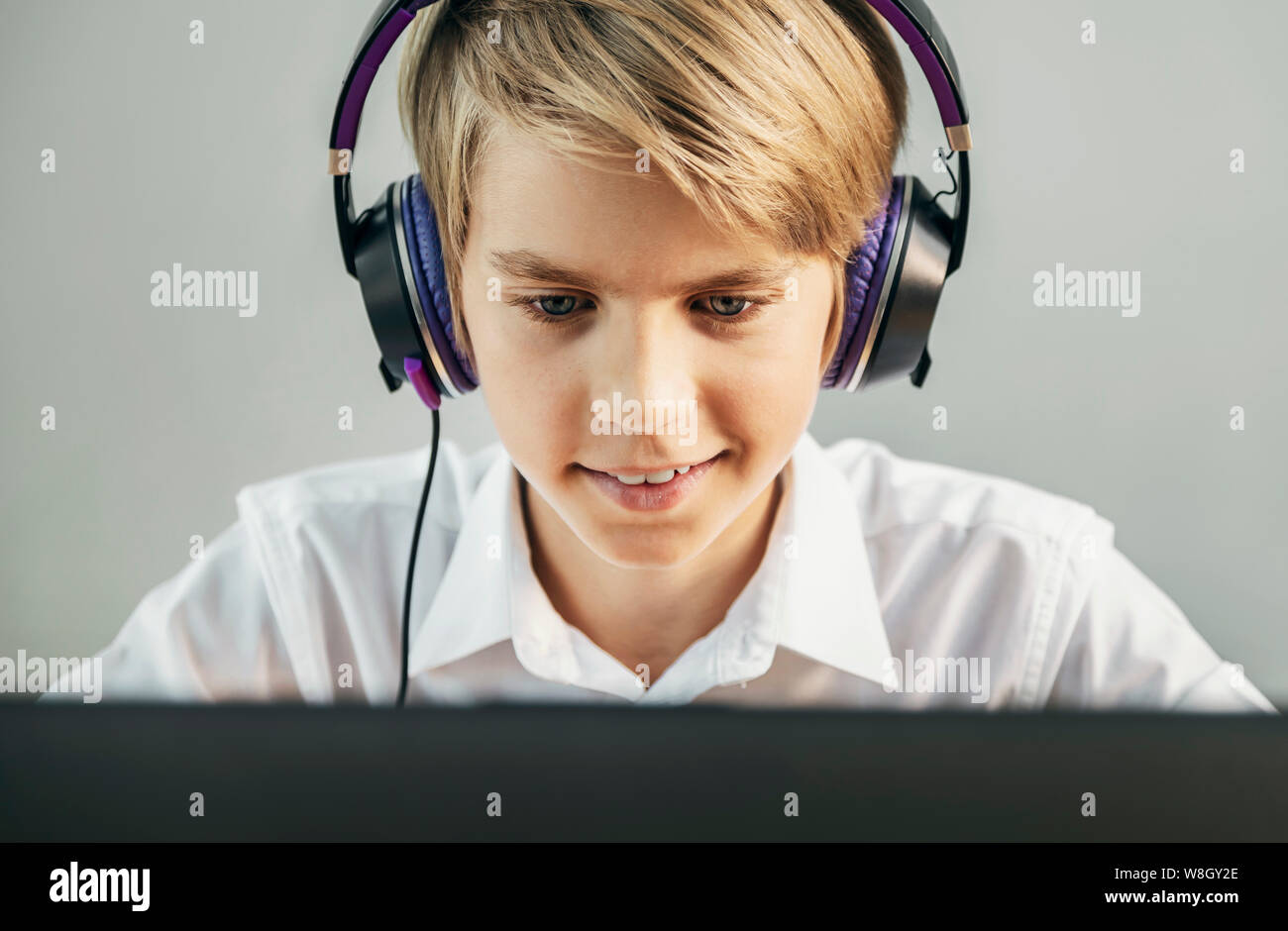 Desiderosi di sorridere boy nelle cuffie guardando lo schermo del computer Foto Stock