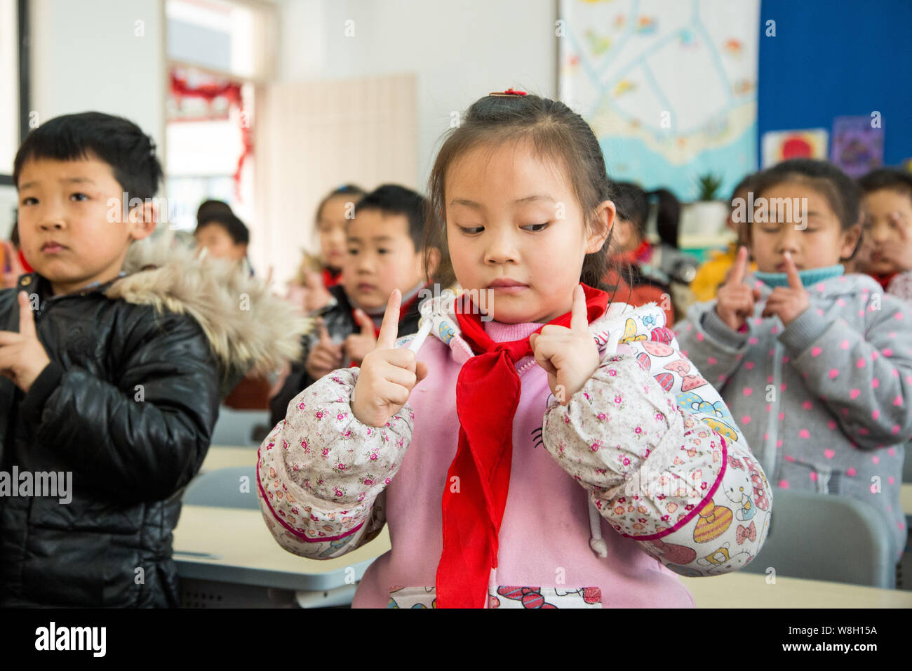 Gli studenti si muovono le loro dita in direzioni diverse e rotolare i loro occhi come essi seguono le dita della mano per la pratica degli esercizi degli occhi in una scuola primaria in ha Foto Stock