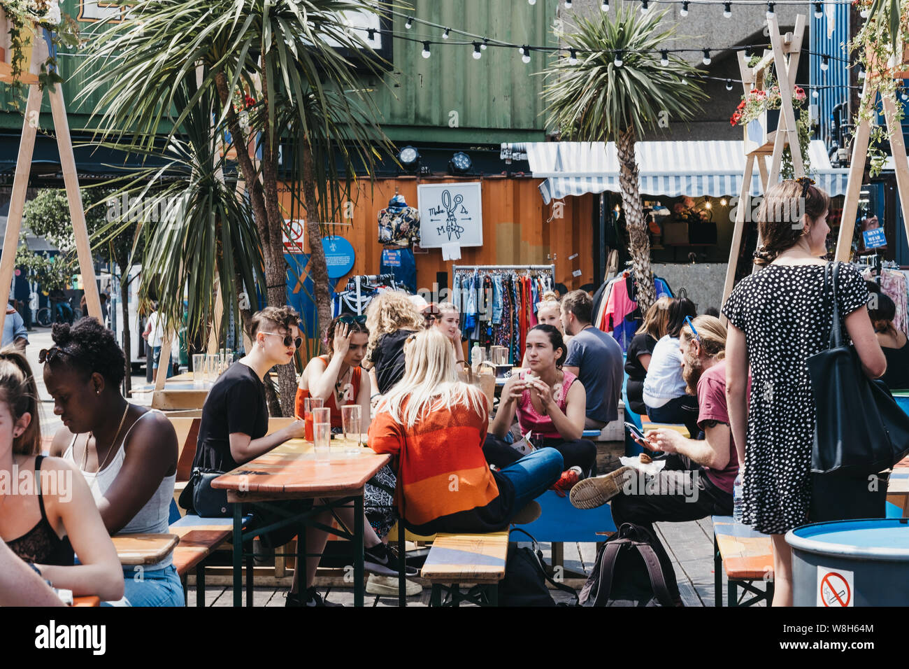 London, Regno Unito - 16 Luglio 2019: persone ai tavoli all'interno di Pop Brixton, luogo dell'evento e la casa di una comunità di rivenditori indipendenti, ristoranti, st Foto Stock