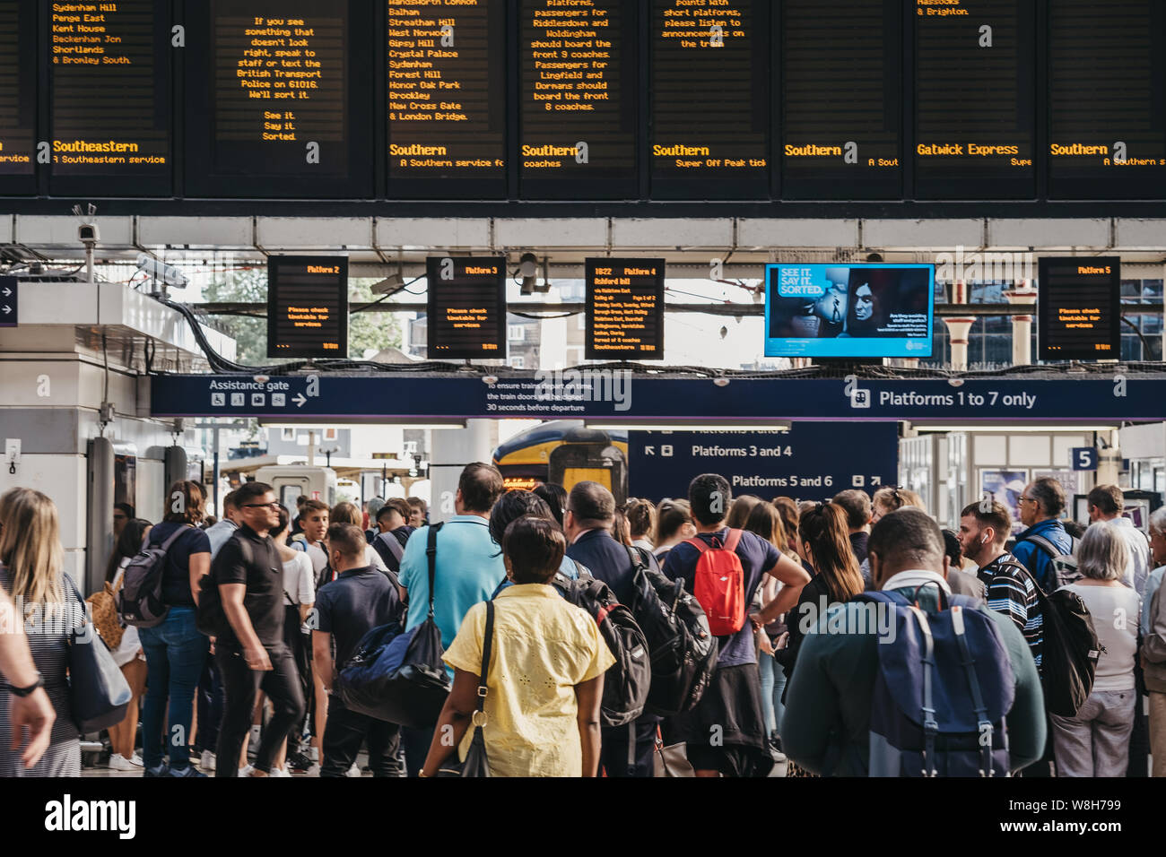 London, Regno Unito - 16 Luglio 2019: persone in attesa per la piattaforma annuncio all'interno della stazione ferroviaria di Victoria, una delle più frequentate stazioni ferroviarie di Londra, Foto Stock