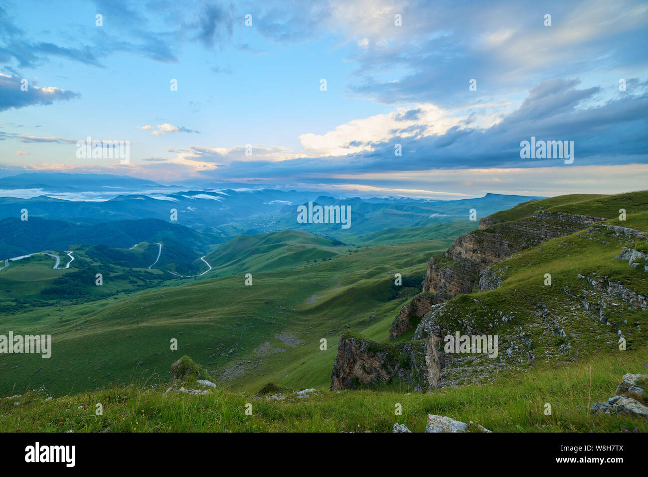 Cumulus nuvole al tramonto su una verde valle di montagna Foto Stock