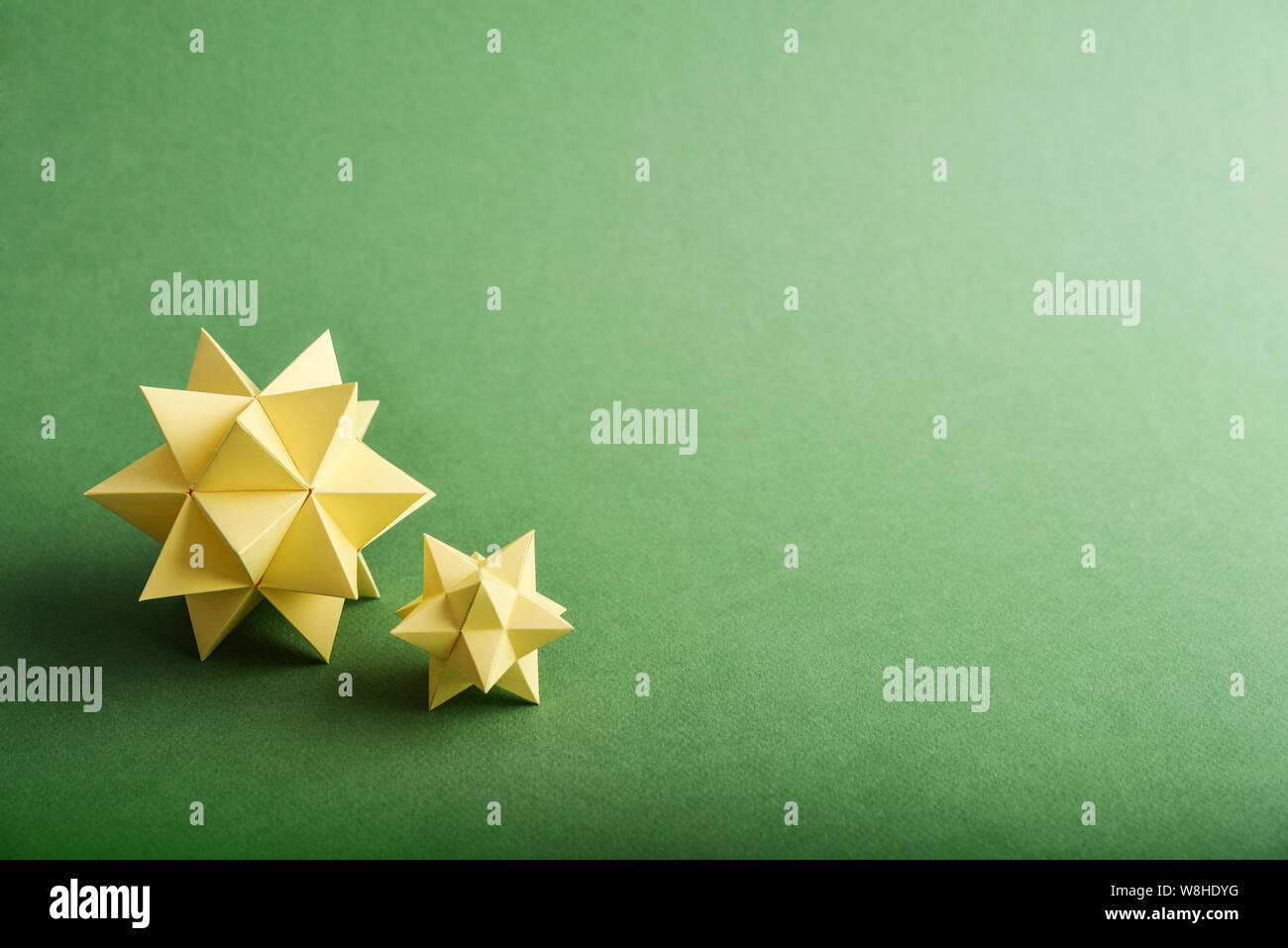 Due fatti a mano carta gialla poliedri su uno sfondo verde. Foto Stock