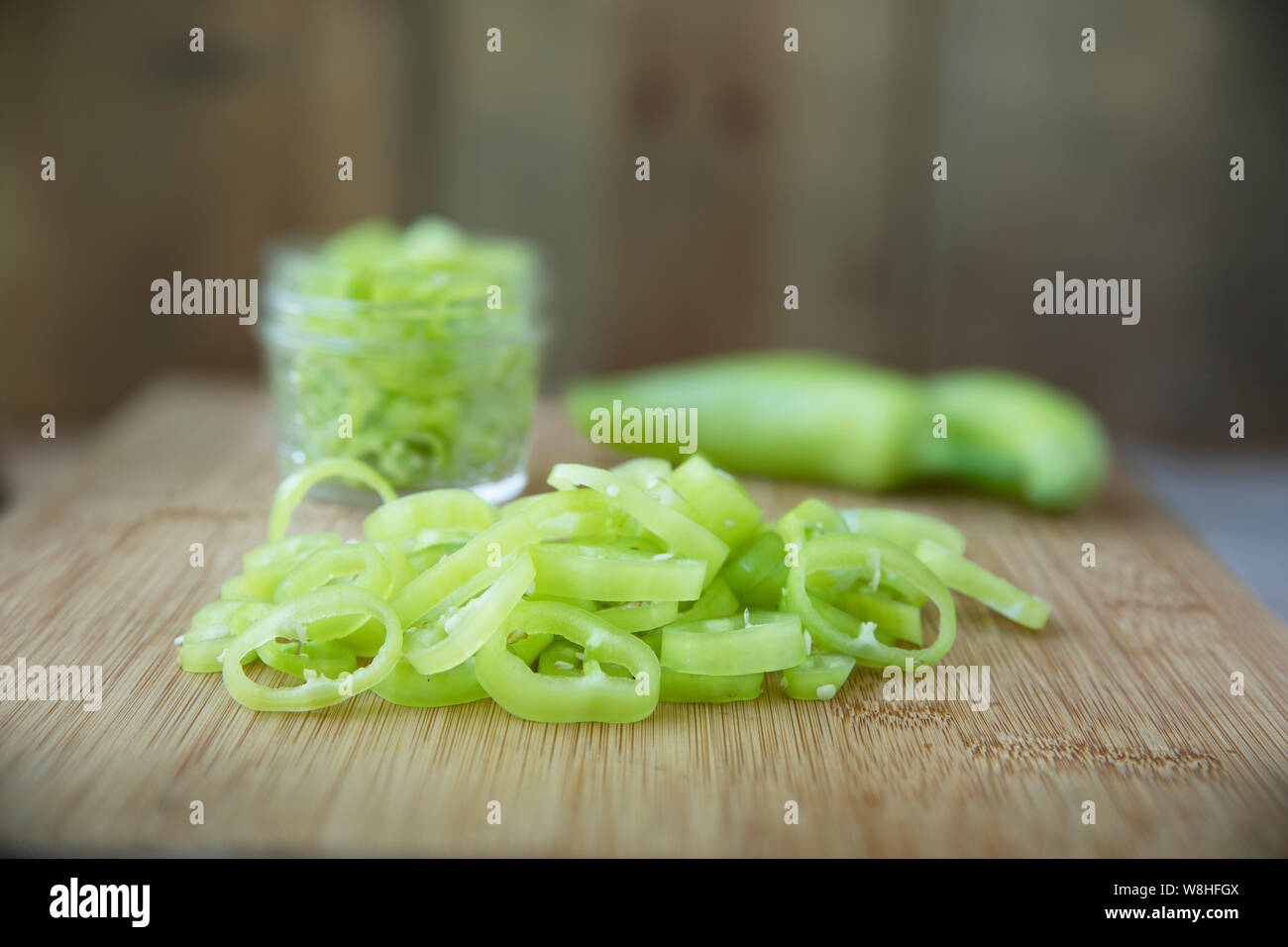 Freschi fette di banana peperoni su un tagliere con i jar pronto per il decapaggio. Foto Stock